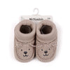 Pair of handmade knitted baby booties resembling a bear face in a light beige color