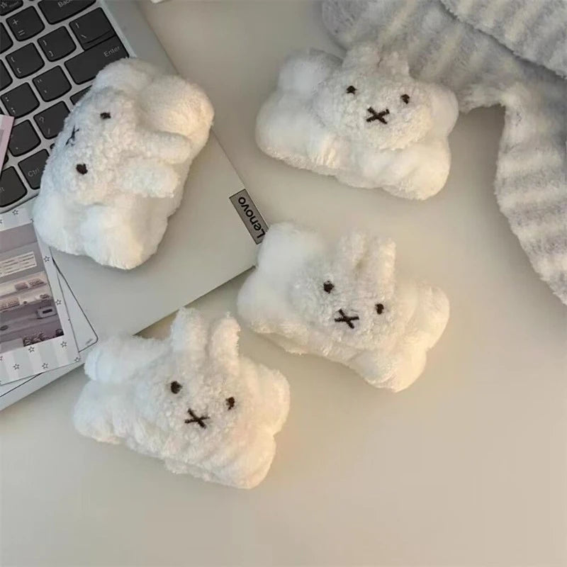 Three white fluffy rabbit shaped waterproof face wiping wristbands resting on a laptop.