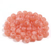 A pile of 50 imitation jade acrylic cloud beads in a translucent pink color for jewelry making.