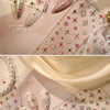 Close-up of sparkling 5D diamond nail art stickers on a translucent background with pearl strands.