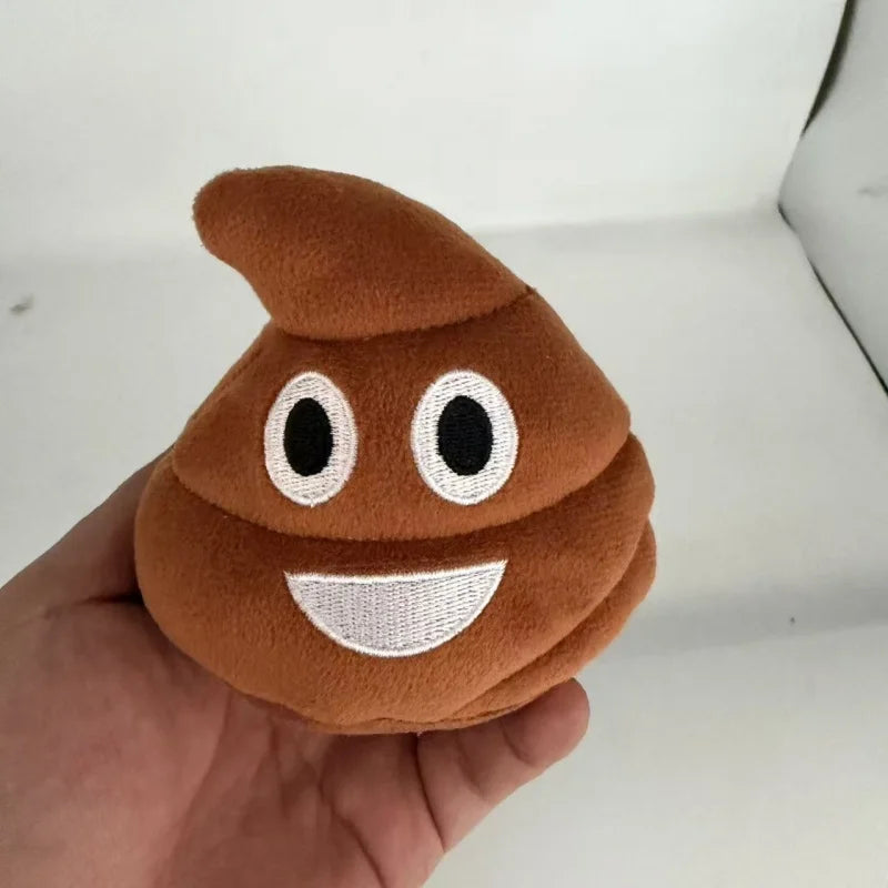 A brown plush toy shaped like a poop with white eyes and a smiling mouth is held in a hand.