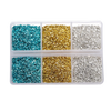 A clear plastic container holding four compartments filled with colored crushed glass stones: blue, gold, silver, and blue ag