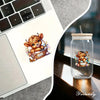 A digital art sticker featuring a cute brown Highland cattle cub in a woven basket, placed on a laptop and next to a glass ja