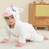 A baby wearing a white unicorn hooded romper with pink accents, sitting on a white rug.