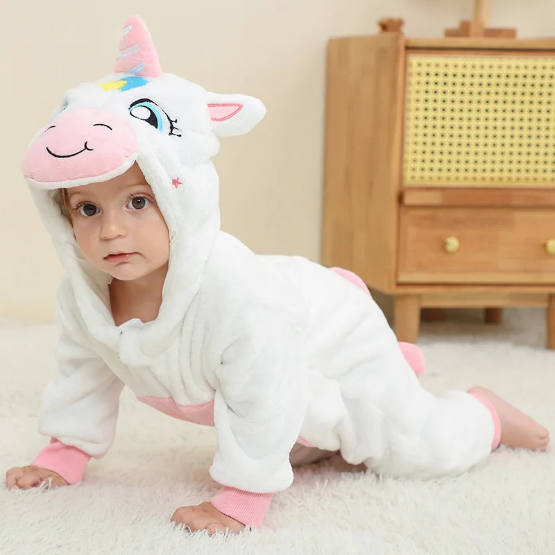 A baby wearing a white unicorn hooded romper with pink accents, sitting on a white rug.