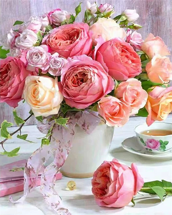 A bouquet of pink and peach roses, sunflowers, and peonies arranged in a vase on a white surface.