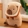 A soft, light brown capybara plush toy wearing an orange and cream outfit, sitting on a wooden surface.