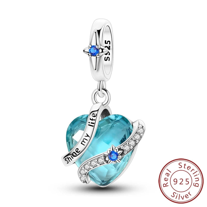 A sterling silver heart charm bead featuring a blue gemstone and engraved text on a silver chain.