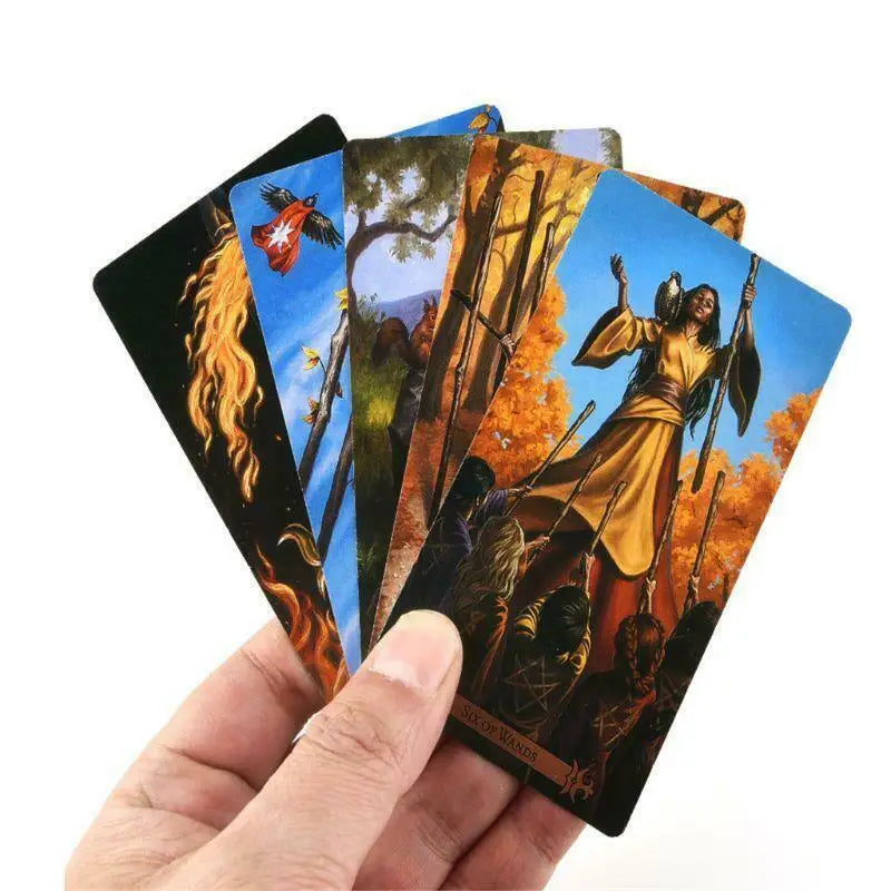 A hand holds a stack of Modern Spellcaster's Tarot Deck cards featuring mystical imagery and gold accents.