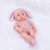 A realistic soft vinyl baby doll with a pink outfit and headband lying on white fluffy fur.