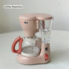 A pink kids pretend play kitchen set featuring a coffee maker, water dispenser, and toaster.