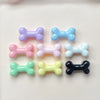 A collection of six small, colorful resin bone charms in various pastel and dark colors for nail art or jewelry making.