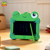 A bright green frog-shaped LCD drawing tablet keychain with a stylus rests on a wooden surface.