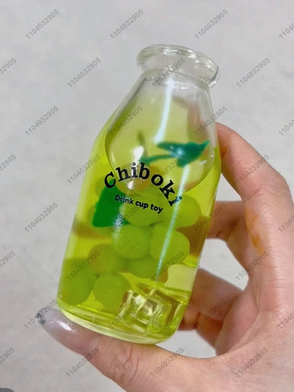 A hand holds a clear bottle filled with green fruit, labeled Chiboki, which is a drink cup toy.