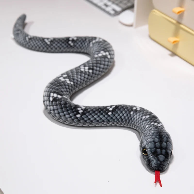 A gray and black lifelike simulation snake plush toy coiled on a white surface.