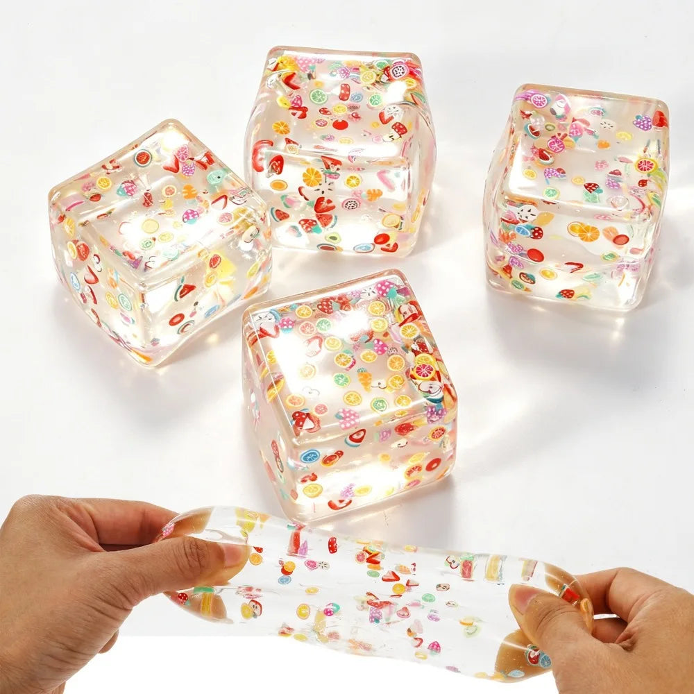 Several clear, colorful fruit ice cubes are shown, some being squeezed by a hand.