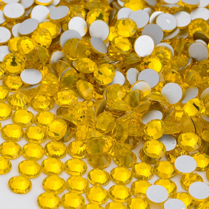 A close-up view of yellow glass crystal flatback rhinestones mixed with white rhinestones.