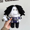 A hand holds a black and white plush toy resembling a rabbit with white wings and a dark blue patterned body.