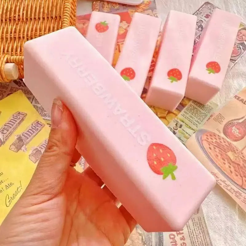 Eine Hand hält ein rosa Erdbeer-förmiges Knetspielzeug zum Drücken für Butter-Pinching und Entspannung.