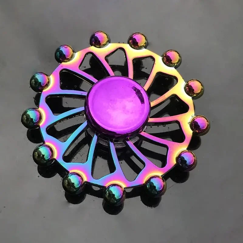A colorful metal fidget spinner with a central purple disc and surrounding metal blades.