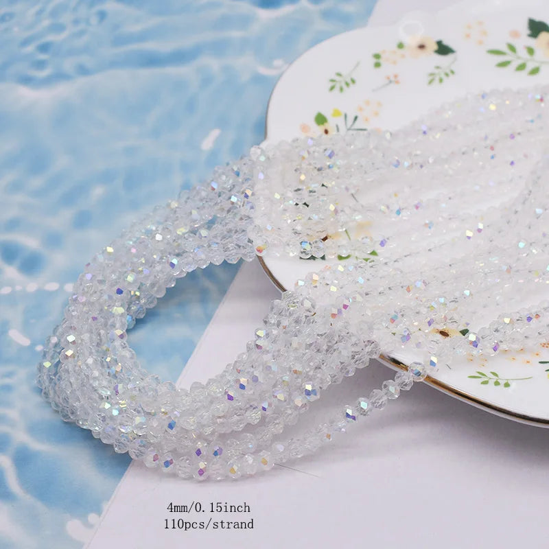 A strand of clear faceted crystal rondelle beads for jewelry making laid on a white surface.