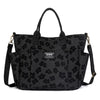 Black canvas tote bag with multiple pockets featuring a floral pattern.