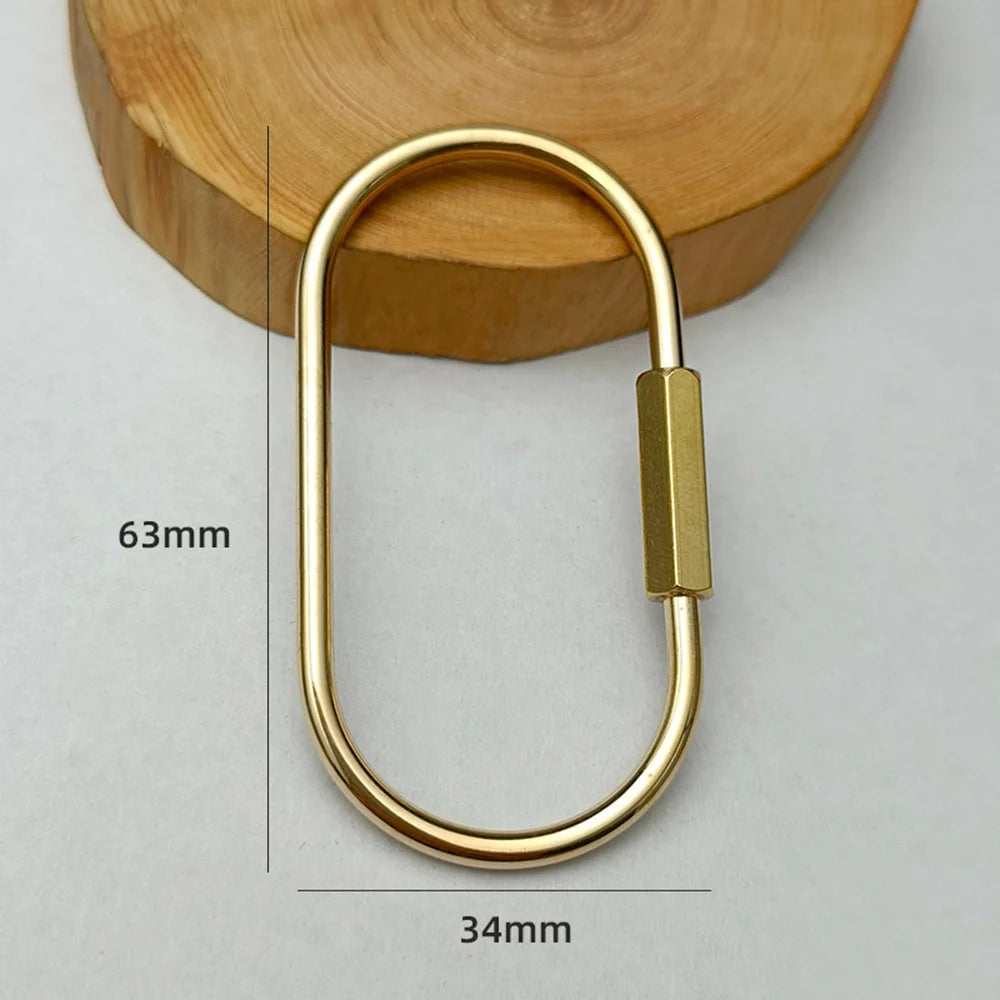 A brass keychain with a locking carabiner clip resting on a wooden surface.