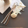 A beaded keychain set featuring a starfish, a seashell, and pearl beads on a white cord.
