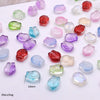 A collection of gradient tulip glass beads in various shades of purple, pink, green, and red scattered on a white surface.