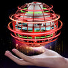 Une main tient un jouet de balle magique tournante avec des lumières LED rouges et vertes créant des anneaux lumineux.