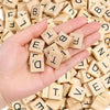 A hand holds several wooden alphabet letter tiles scattered among many more.