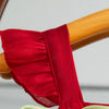 A red pleated dress and sleeveless outfit for a baby girl is shown attached to a wooden item.