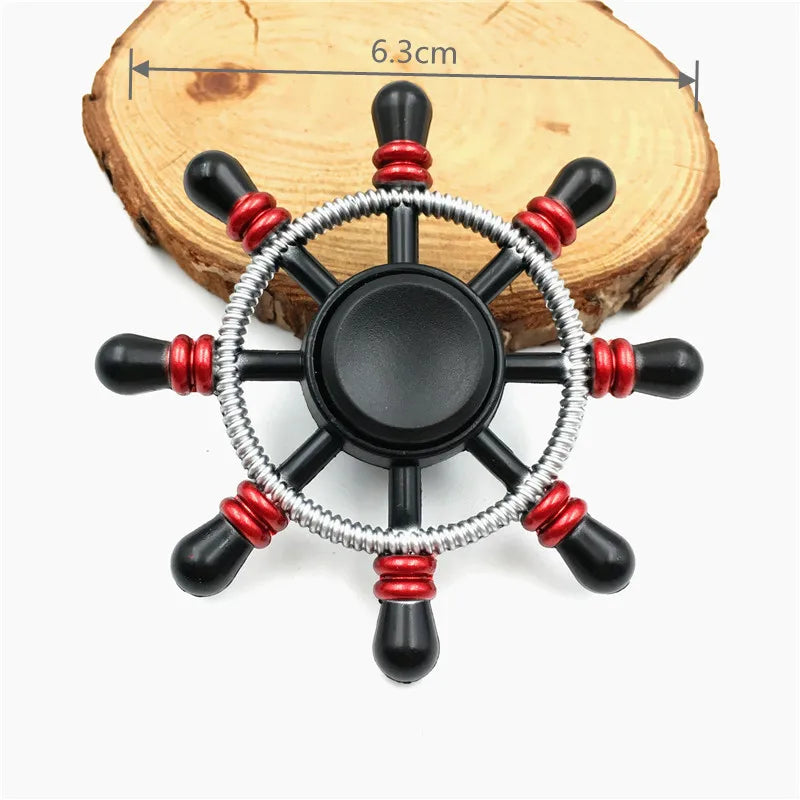 A black metal fidget spinner with a silver ring and red accents rests on a wooden surface.