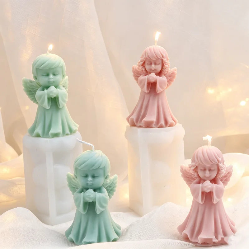 Three silicone praying angel molds in mint green and pink are displayed on white candles.