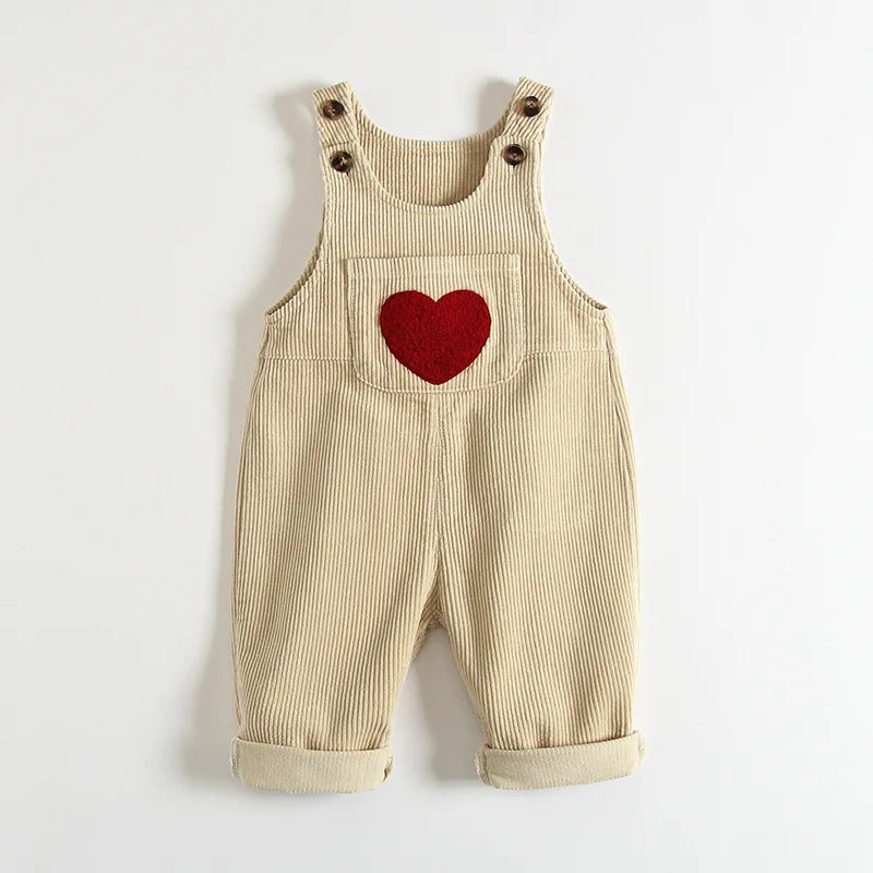 Tan corduroy overalls for a toddler featuring a red heart embroidery on the chest.