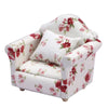 A white mini sofa and pillow set with a floral pattern featuring red roses for a dollhouse.