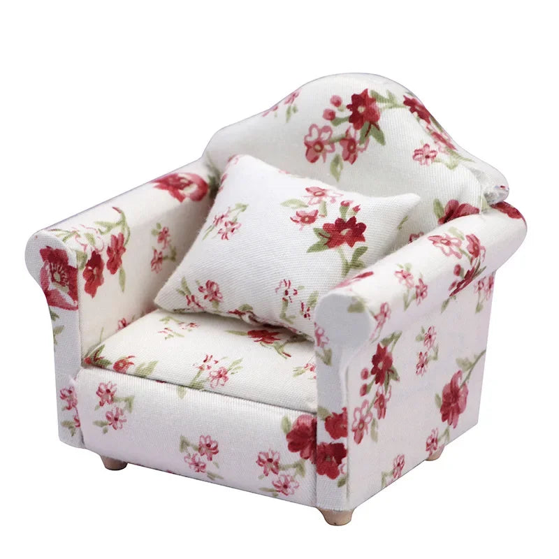 A white mini sofa and pillow set with a floral pattern featuring red roses for a dollhouse.