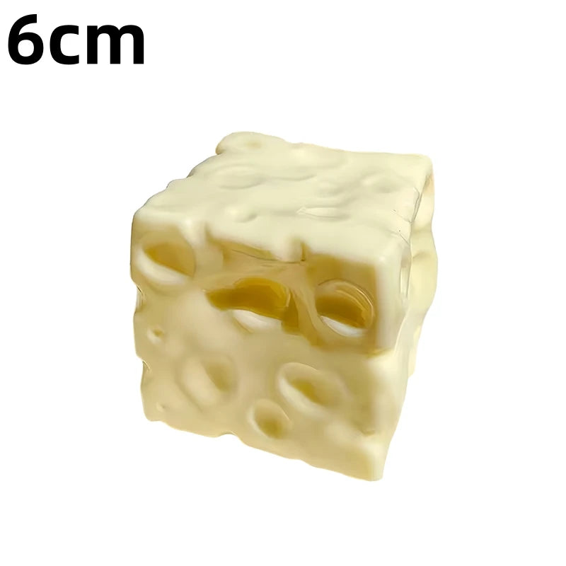 A pale yellow squishy cheese cube stress ball with visible holes.