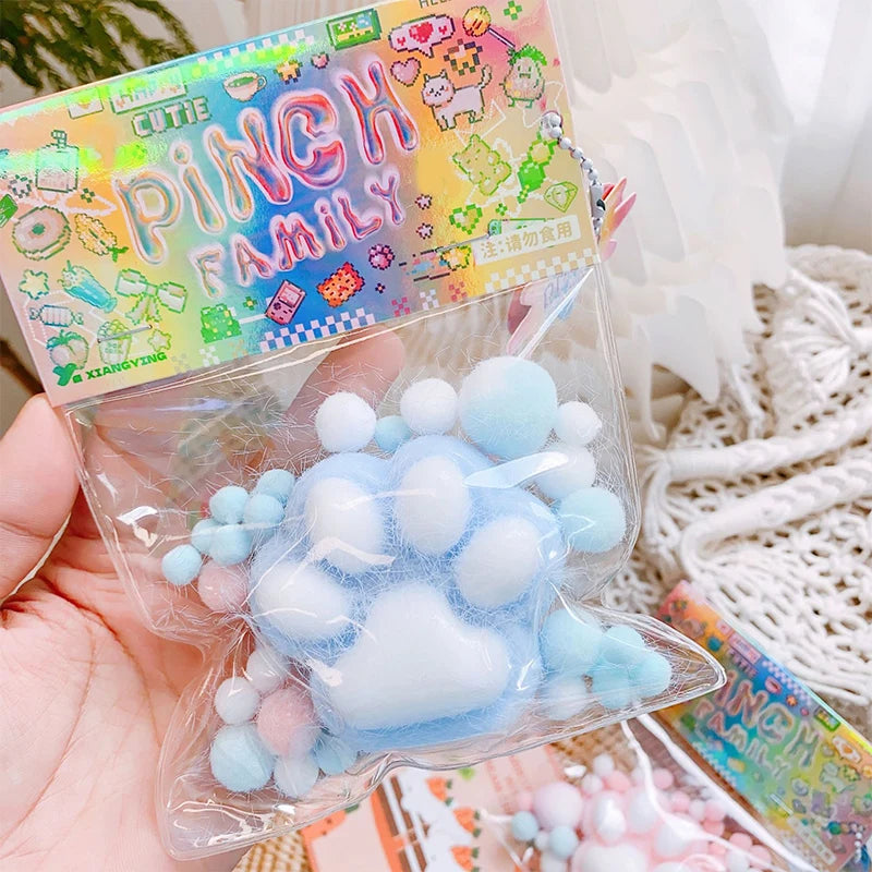 A clear plastic bag contains a light blue and pink squishy toy shaped like a cat paw, packaged for stress relief.