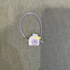 A purple necklace with a small camera pendant and charm for a Labubu doll.