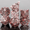 A stack of seven skull and dragon metal dice showing intricate designs and reflections.