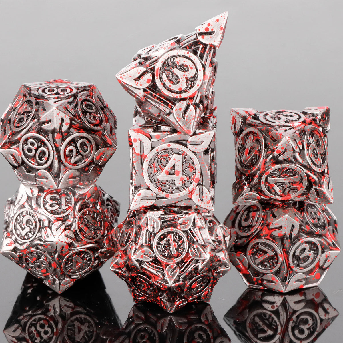 A stack of seven skull and dragon metal dice showing intricate designs and reflections.