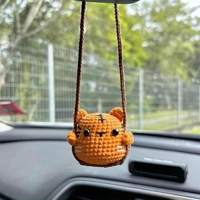 Handmade crochet orange tiger hanging ornament suspended from a string inside a car