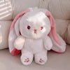 A white plush bunny toy with pink ears and pink feet sitting on a light surface.