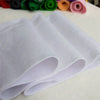 A stack of white soft felt fabric sheets rolled up, next to colorful felt rolls.