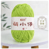 A ball of bright lime green chenille yarn with Chinese characters on the label, displayed on a white surface.