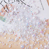 A pile of mixed resin rhinestone pearls with an AB finish scattered on a wooden surface.