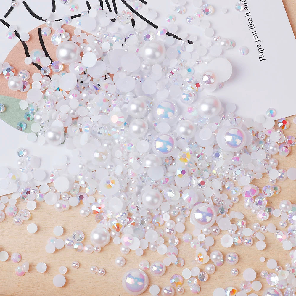 A pile of mixed resin rhinestone pearls with an AB finish scattered on a wooden surface.