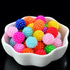 A bowl filled with various brightly colored acrylic pearl beads for jewelry making