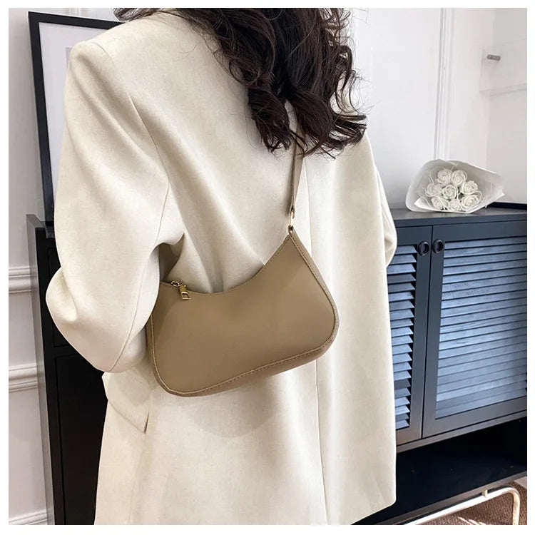 A beige PU square crossbody bag with a zipper closure is shown next to a light colored coat.
